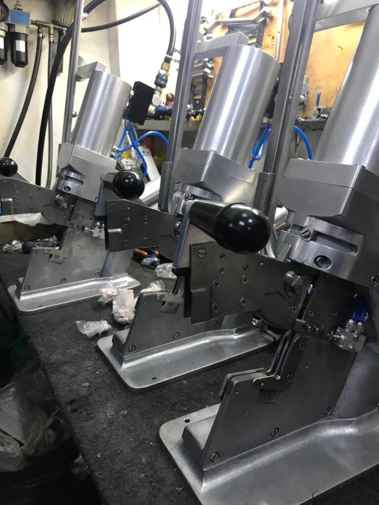 Grampeadeiras pneumáticas para fechamento de embalagens industriais Grampos e Grampeadeiras pneumáticas alinhadas em bancada de produção industrial
